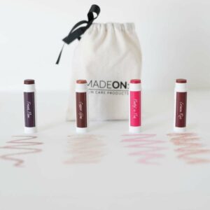 tinted lip balms in french plum, copper, crimson and pink, lined up and showing the color 